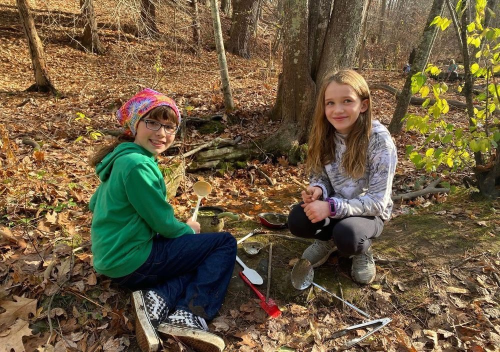 Two girls making mud soup in the fall woods