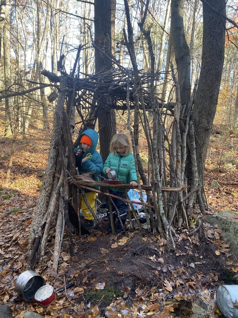 Two preschoolers cooking in a stick fort mud kitchen