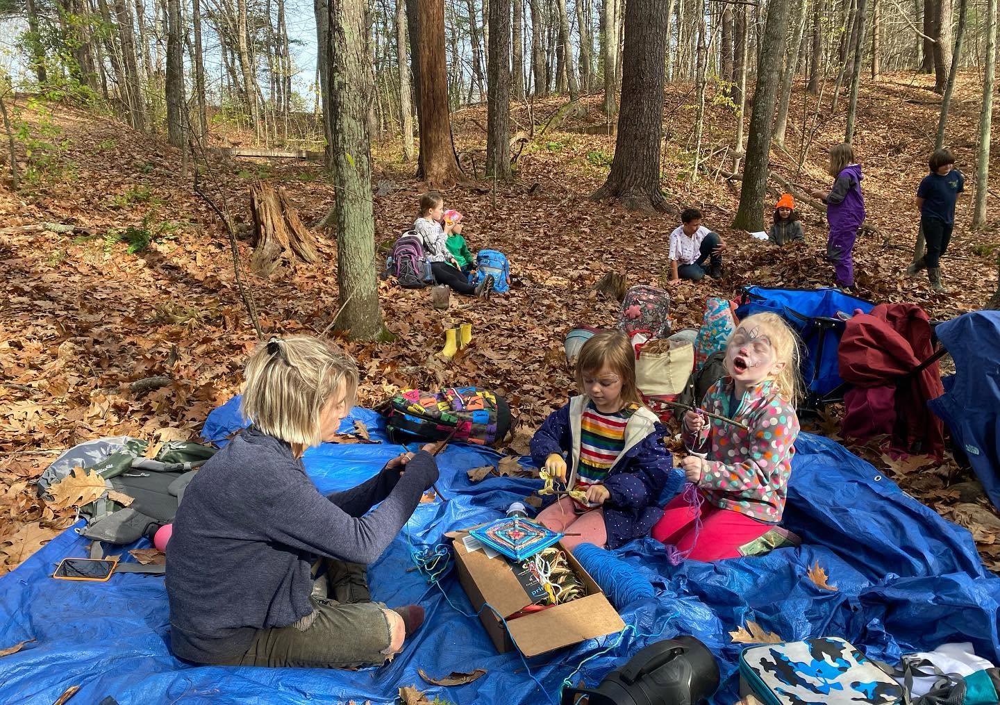 Kids weaving and playing on a tarp in the fall woods